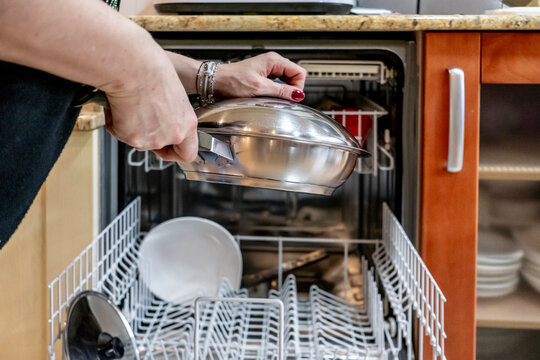 Woman loading dishwasher with stainless steel pot
