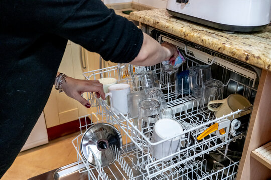 Loading a dishwasher with various kitchenware items