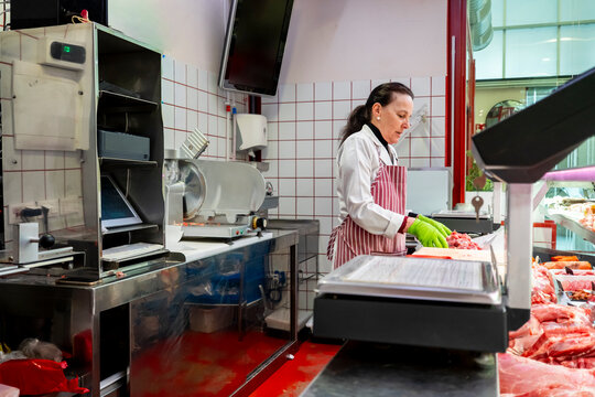 Female butcher working in a professional meat shop