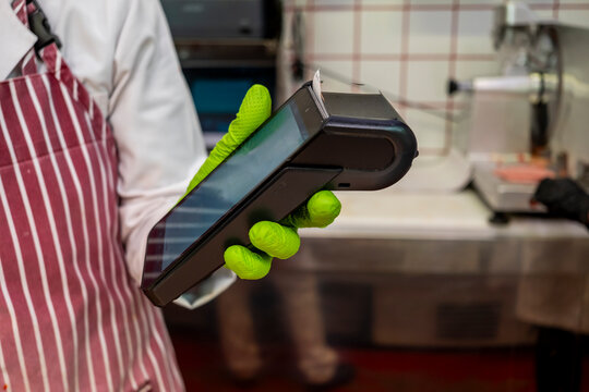 Worker with card reader in butcher shop using gloves