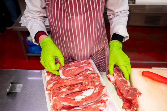 Butcher with striped apron sorting meat cuts