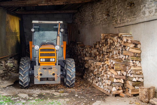 Tractor in barn next to neatly stacked cut wood