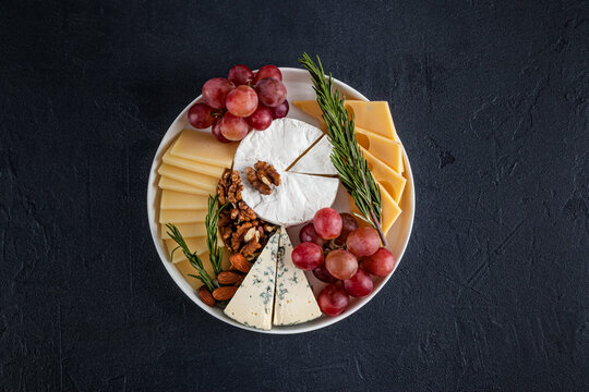 Cheese platter with grapes, nuts, and herbs