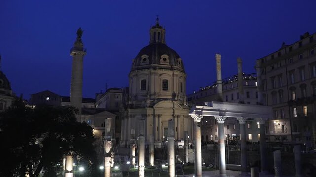 columns from the remains of a roman basilica with generic Renaissance building (Le Domus Romane di Palazzo Valentini) in the background, at night, in Rome Italy