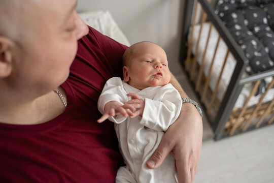 Newborn in arms at home in cozy setting