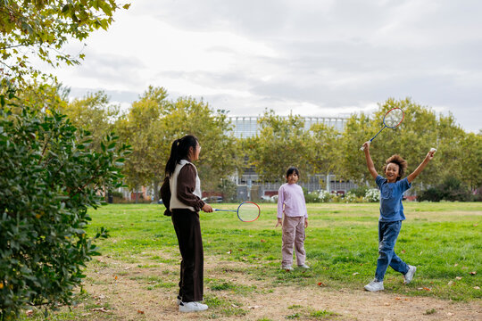 Children playing badminton in a sunny park