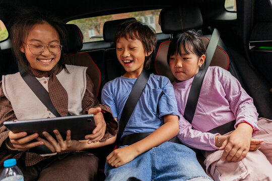 Asian children enjoying time together in car