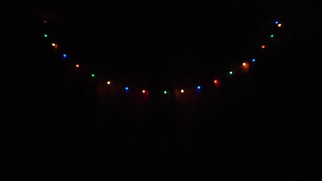 Colorful string lights glowing softly in a dim interior. Warm festive decor and vibrant light play.