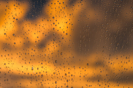 Raindrops on glass with vibrant sunset background