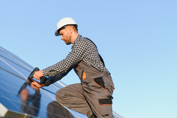 Naklejka premium Man installer installing photovoltaic solar moduls. Concept of alternative and renewable energy