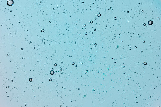 Blue water bubbles floating in clear liquid background
