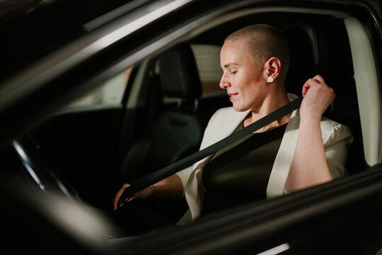 Woman buckling up seatbelt in car, prioritizing personal safety and responsible driving at night