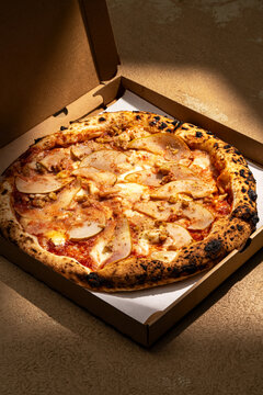 Gourmet pear pizza in open box with warm lighting