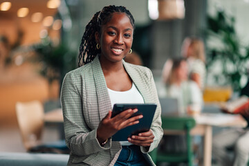 Fototapeta na wymiar Black businesswoman smiling, holding tablet in modern office