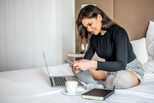 Woman in hotel room working on laptop and phone