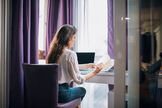 Woman reading by window in modern hotel room