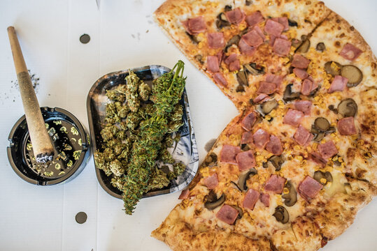 Cannabis, pizza, and joint on a tabletop setting