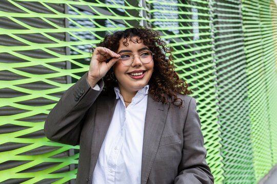 Confident businesswoman with curly hair in modern setting