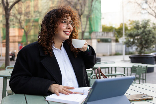 Curly-haired woman drinking coffee at outdoor cafe