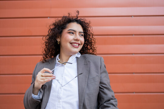Confident businesswoman with curly hair and glasses