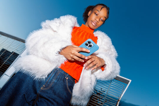 Gen Z girl in bright outfit using smartphone