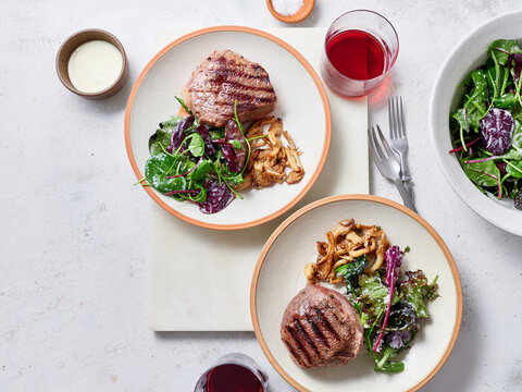 Sliced chuck steak with salad, mushrooms and wine.