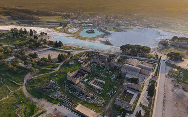 Fototapeta premium Aerial drone view of Hierapolis Antik Kenti and the famous Pamukkale travertines in Denizli, Turkey, showing ancient ruins, Roman theater, columns, and scenic landscape from above.