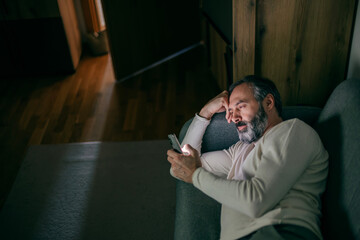 Mature man feeling lonely using phone at night