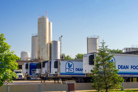 O&rsquo;Fallon, IL &mdash; June 1, 2018: Refrigerated trucks and trailers at a Dean Foods dairy processing facility with large industrial storage tanks and loading docks used for milk distribution