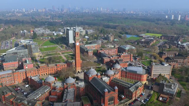 Aerial video featuring the Old Joe clock tower at the University campus of Birmingham and the city skyline covered in thin fog. 