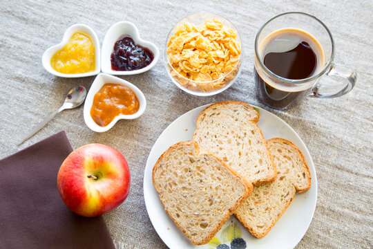 Pane morbido a fette, marmellate, mela rossa, caff&egrave; e cereali