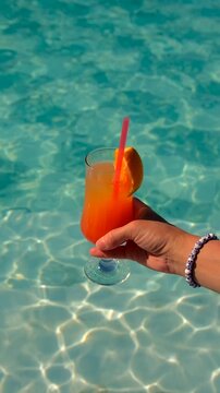 Woman in the pool with a cocktail. Selective focus.