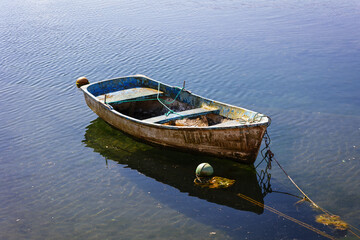 Small fishing boat moored and floating on calm water