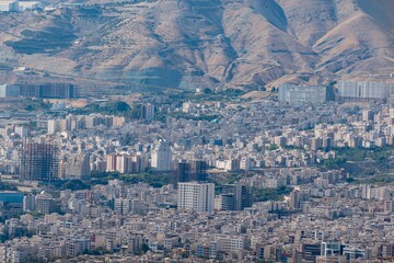 Obraz premium Tehran cityscape with dense buildings and arid mountains in the background