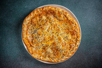Golden baked meat pie with sesame topping