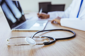 Doctor at Desk With Stethoscope and Laptop Preparing Patient Notes in Medical Office