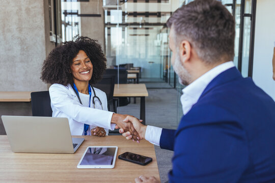 Female Doctor Shaking Hands With Male Patient In Professional Medical Consultation Office Setting