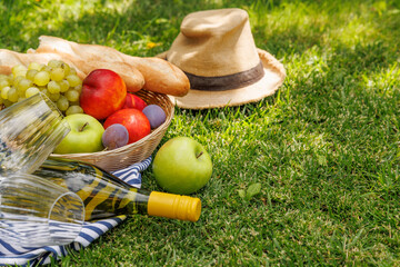 Naklejka premium Picnic with wine, fruits, and baguette on a green meadow