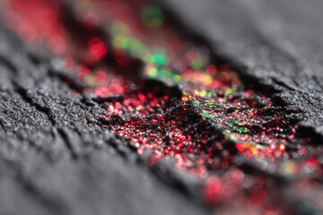 Fototapeta premium Macro shot reveals the intricate details of a textured, sparkling surface with vibrant red and green bokeh, creating an artistic, abstract background for design purposes.