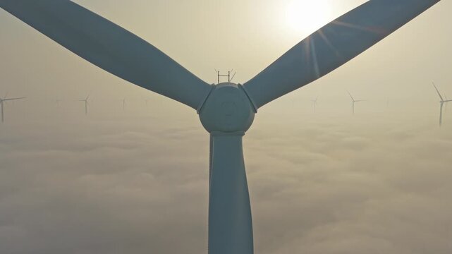 Aerial view of a wind farm above the clouds at sunrise. Wind turbines generating clean, renewable energy for a sustainable future