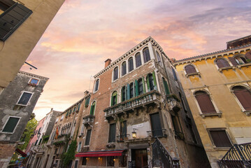 Historic brick Venetian palazzos at Calle Larga corner under sunset sky