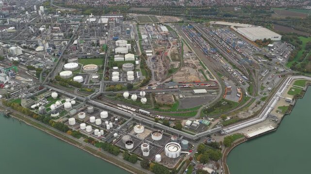 High altitude aerial view of the massive basf chemical plant, a sprawling industrial complex with oil storage tanks, a freight terminal, and harbor on the rhine river