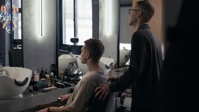 Young Caucasian barber greeting client, shaking hand and listening to clients haircut desire
