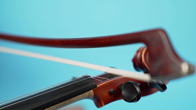 Violin headstock and bow close-up against a light blue background, blurred