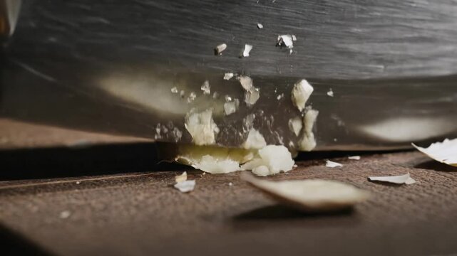 Slicing garlic with a knife on a wooden cutting board in a kitchen setting in close-up