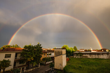 Fototapeta premium Vibrant Vertical Rainbow Over European Rooftops at Golden Hour