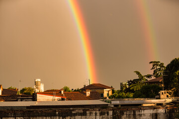 Fototapeta premium Vibrant Vertical Rainbow Over European Rooftops at Golden Hour