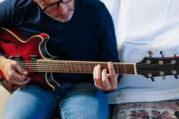 Obraz premium Mid adult man playing electric guitar at home