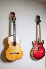 Naklejka premium Acoustic and electric guitars hanging on white wall