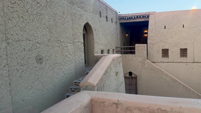 Historic Bahla Fort built with traditional mud architecture standing on rocky ground under clear blue sky showing ancient Omani heritage. Bahla, Oman - February 17 2026